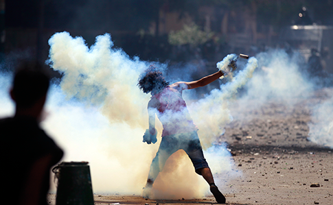 An Egyptian protester throws a tear gas canister toward riot police during clashes near the U.S. Embassy in Cairo, Egypt, Sept. 13, 2012. (AP)