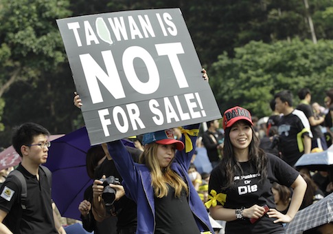 Protesters display a banner denouncing the controversial China Taiwan trade pact / AP