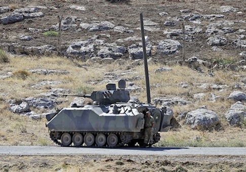 A Turkish soldier stands by a tank as he patrols the border with Syria