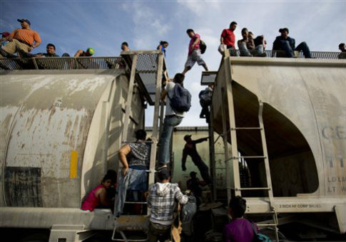 Central American migrants climb on a north bound train during their journey toward the U.S.-Mexico border / AP