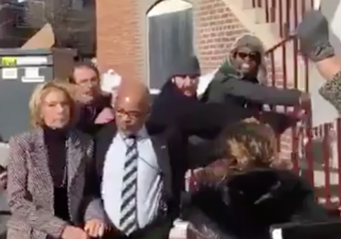 Sec. of Education Betsy DeVos, left, escorted away from protesters / Twitter video screenshot