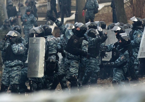 Riot police officers throw stun grenades at anti-government protesters