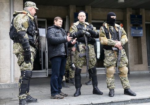 A local resident talks to pro-Russian armed men standing guard outside the mayor's office in Slaviansk
