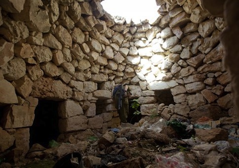An Israeli soldier inspects a stone structure as they search for three missing Israeli teens