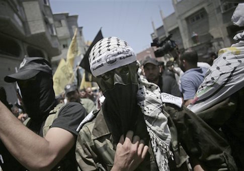 A masked militant wears a head band with Arabic writing that reads "the martyr, Abdul Qader Al-Husaini brigades" during the funeral of two Fatah militants, Marwan Sleem and Mazin Al-Jarba, who were killed by an Israeli airstrike, in Bureij refugee camp, central Gaza Strip, Monday, July, 7, 2014