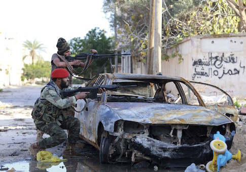 Pro-government Libyan forces, who are backed by locals, aim their weapons during clashes in the streets with the Shura Council of Libyan Revolutionaries, an alliance of former anti-Gaddafi rebels, who have joined forces with the Islamist group Ansar al-Sharia, in Benghazi December 28