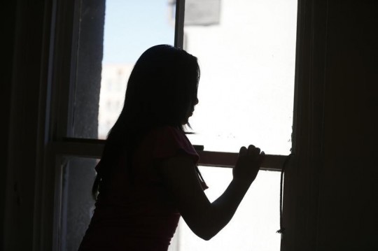 Maria, an undocumented migrant from Central America, looks out of a window in Los Angeles