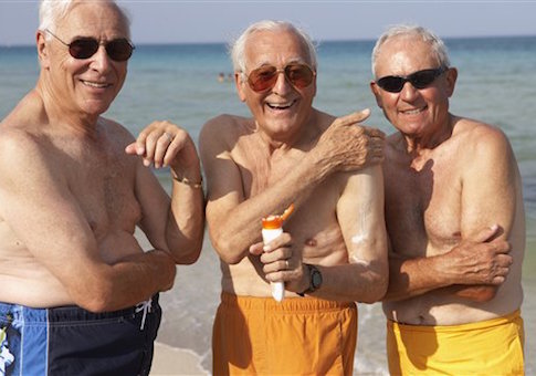 Senior men applying sunscreen on beach