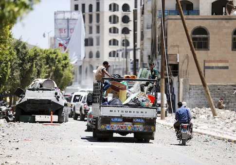People ride on the back of a truck with their home's furniture as they move from a neighbourhood after an air strike by a Saudi-led coalition struck a nearby missile base, in Yemen's capital Sanaa April 23