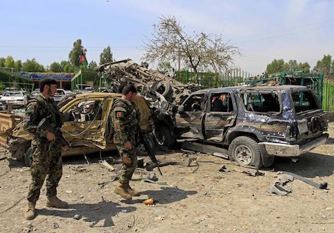 Afghan National Army (ANA) soldiers inspect the wreckage of vehicles at the site of a suicide attack that targeted a NATO convoy in Jalalabad city