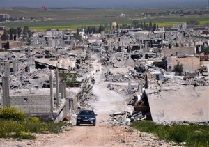 In this picture taken on Saturday, April 18, 2015, a car passes in an area that was destroyed during the battle between the U.S. backed Kurdish forces and the Islamic State fighters