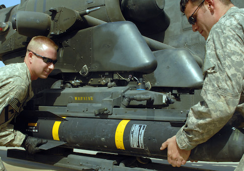 Soldiers mount a Hellfire missile onto an Apache helicopter