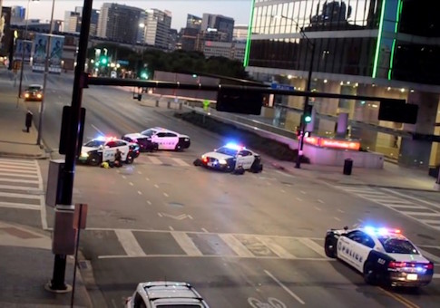 Police officers take cover behind their vehicles while under fire in downtown Dallas