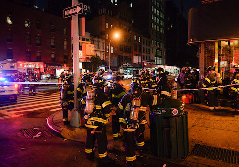 New York City firefighters stand near the site of an explosion in the Chelsea neighborhood of Manhattan, New York