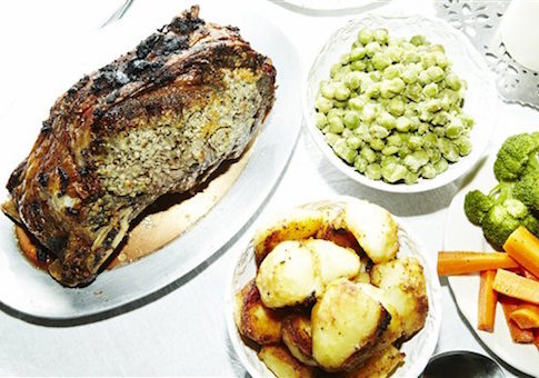 Dinner meal of roast meat with potatoes, carrots, broccoli and broad beans on table