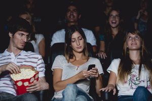 woman using a cell phone in a movie theater