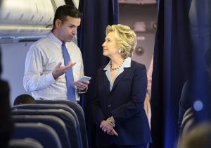 Hillary Clinton looks at a smart phone with national press secretary Brian Fallon / Getty Images