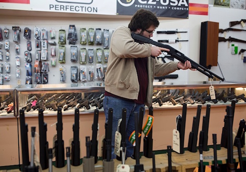 A customer sights a shotgun at a gun shop