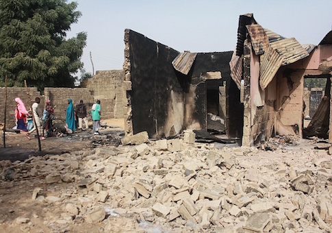 A group of children walk past rubbles and remains of a house following a Boko Haram attack
