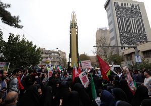 Iranians gather next to a replica of a Ghadr medium-range ballistic missile