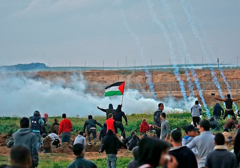 Palestinians run through tear gas fumes during clashes following a demonstration along the border with Israel east of Gaza City