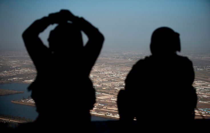 U.S. Army helicopter crew members look out of their Chinook helicopter as they fly from the U.S. Embassy to Baghdad International airport
