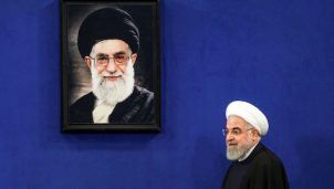 Iranian President Hassan Rouhani walks past a portrait of Supreme Leader Ayatollah Ali Khamenei