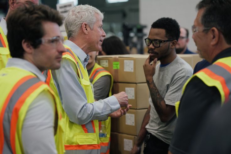 Wright speaks with one of the factory's 250 workers following his remarks.