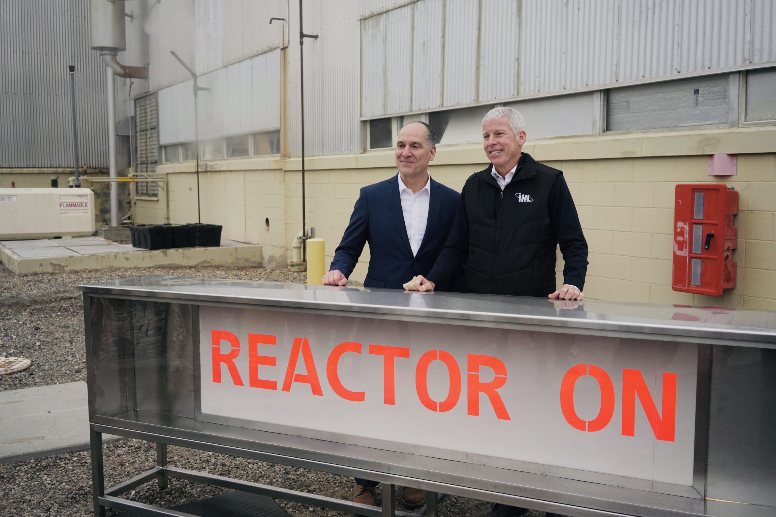 Wright and Wagner pose for a photo outside the INL National Reactor Innovation Center's Demonstration of Microreactor Experiments, which is being used to accelerate the development of advanced nuclear energy technologies.